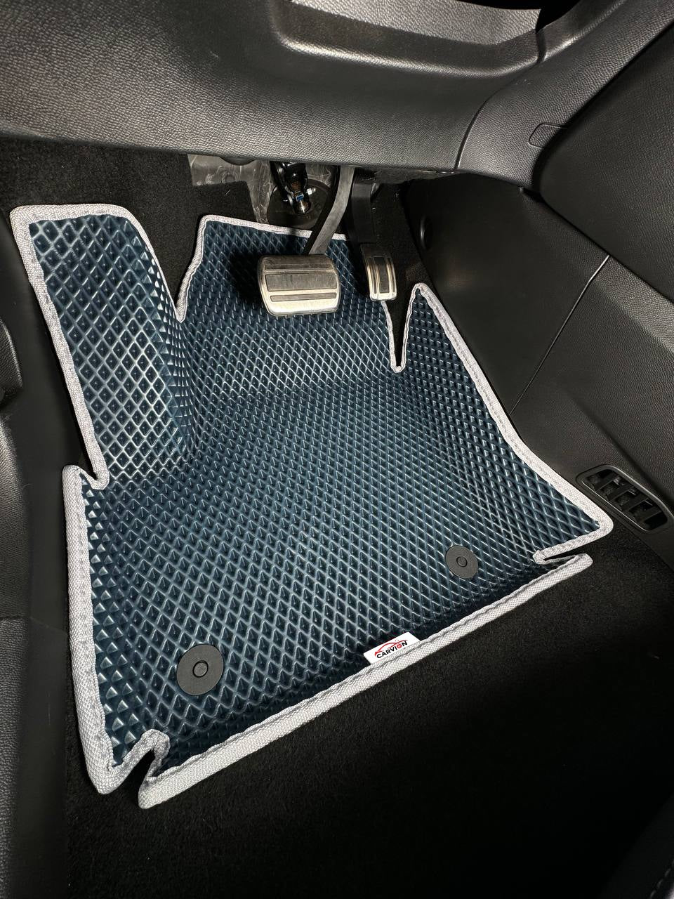 Illustrative photo: navy 3D EVA mat with raised edges and grey trim in the driver's footwell